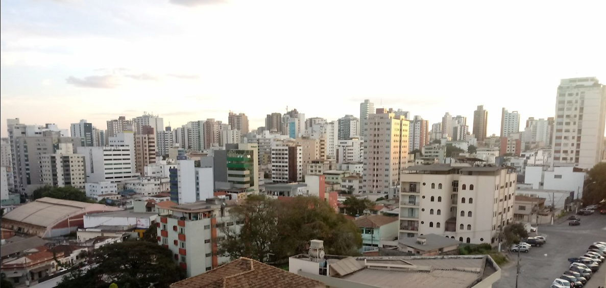Um bairro com muitos prédios e casas e céu claro